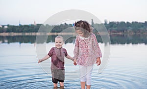 Children walk together on the bank of the lake. Active family walk