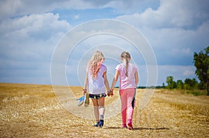 Children walking in golden fields together hand in hand