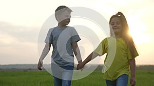 children walking a in the park. boy and girl are holding hands walking on the grass in the park at sunset. happy family