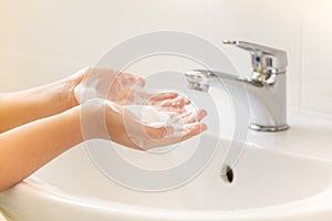 Children washing hand with foam soap in bathroom sink