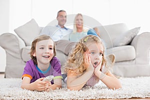 Children watching TV while parents sitting on sofa