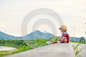 A children wear hat and sitting on the gound and flower near him.