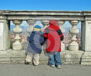 children in winter jackets looking at the city through the balus