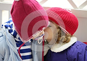 Children, winter red hat whispering in ear