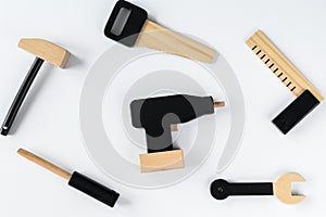 Children wooden tools on a white background,  a drill in the center of the composition. The concept of diy