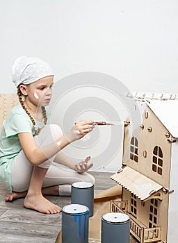 Children at work: The girl neatly paints the facade of the doll house with a small tassel in white.