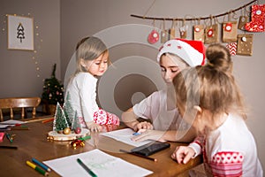 Children write letter to Santa Claus at home. sisters girls draw on background of Christmas devoration