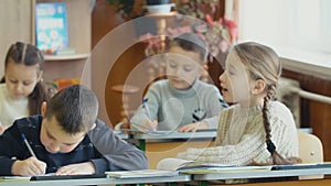 Children write sitting at a desk