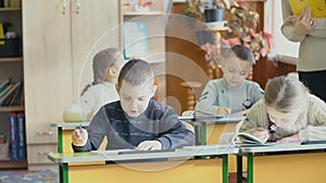 Children write sitting at a desk