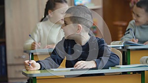 Children write sitting at a desk