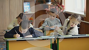 Children write sitting at a desk