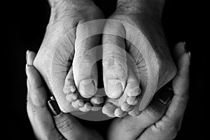 Children& x27;s foot in the hands of mother, father, parents. Feet of a tiny newborn.