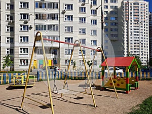 children& x27;s playground with swings in courtyard of residential building in the city, Russia