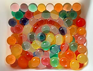 Children toys of colorful water bread are placed in a white container