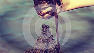 Children, youngster and the parent together build a sand castle on the water.