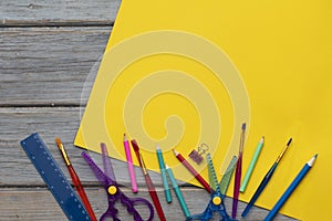 Childrens art and craft composition. Art supplies and yellow paper on a desk