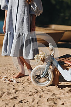 childrens bike with a basket and a woman in a blue dress on the sand