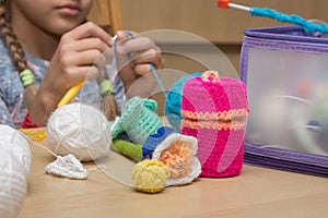 Childrens crafts-embroidery lying on the table, in the background the girl knits