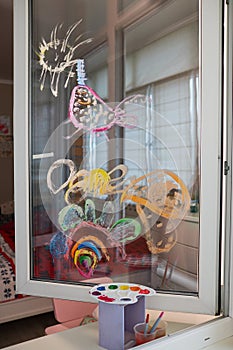 Childrens drawing on the glass window with paints. The concept of home self-isolation. Young artist