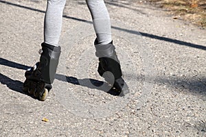 Childrens feet in roller skates standing uncertainly on the road, rear view