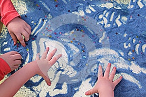 Childrens hands touching blue sand on white table sand therapy, development of fine motor skills