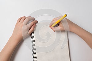 Childrens hands writing in notebook. Child doing homework. Top view white background