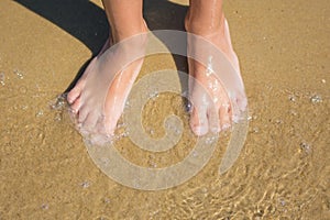 Childrens legs close-up on the edge of the water sandy beach sea shore