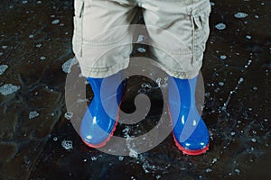 Childrens legs wearing blue rubber boots and