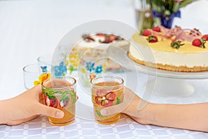 Childrens party.  Children`s hands and juice in a glass.  On the table is cake.