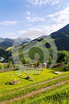 Childrens playground with swing, slide, roundabout, sandpit, goal, playhouse, mountains