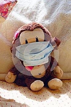 A childrens plush stuffed animal toy wearing a face mask