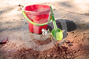 Childrens red bucket and shovel, summer leisure games on the beach