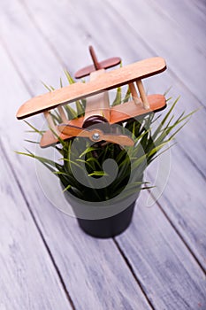 Childrens toy airplane on the flowerpot on the wooden background.