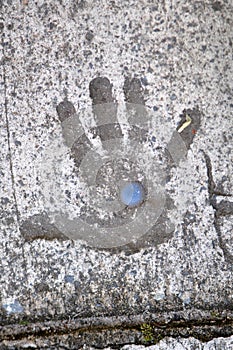 Childs hand in cement concret with blue stone