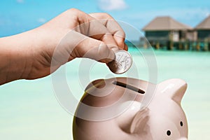 A childs hand puts one ruble into a piggy bank. How much money do you need for sea holidays for Russian tourists