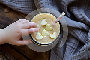 childs hand reaching for a smoothie with heartshaped apple pieces