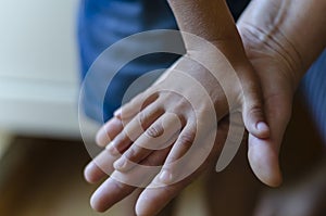 A childs hand rests on top of an adult palm
