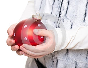 Childs hands holding red christmas ball