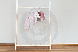 Childs minimal fashion in pastel clothes. Stylish baby or kid pink blouse, sweater, cardigan, pants on hanger in nursery