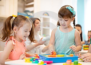 Childs playing with developmental toys at table in kindergarten photo