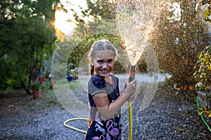 Childs playtime outdoors with a water hose at sunset, creating a magical summer scene.
