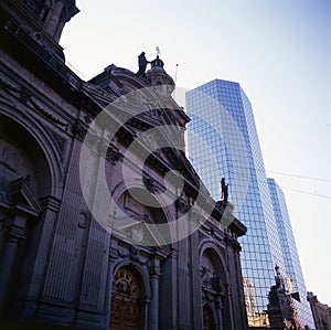 chile city's cathedral and a mirrored modern building seen from below, comparative architecture,luxury and vintage