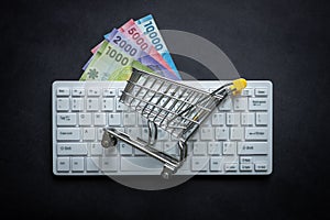 Chile currency, White computer keyboard, Miniature shopping cart, Black background, Online shopping concept in stores, Low prices