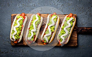 Chilean Completo Italiano. Hot dog sandwiches with tomato, avocado and mayonnaise on wooden board. Top view. photo
