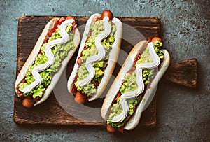 Chilean Completo Italiano. Hot dog sandwiches with tomato, avocado and mayonnaise on wooden board. Top view. photo