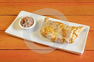 Chilean Creole empanada with purple onion and parsley accompaniment on white plate