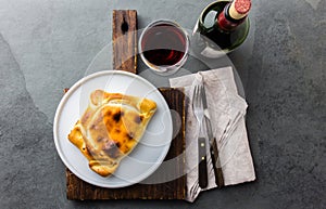 Chilean empanada served on wite plate with red wine. Top view