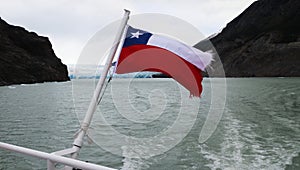 Chilean flag blowing in the wind on Lake Gray, Patagonia, Chile