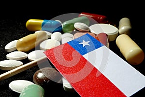 Chilean flag with lot of medical pills isolated on black background