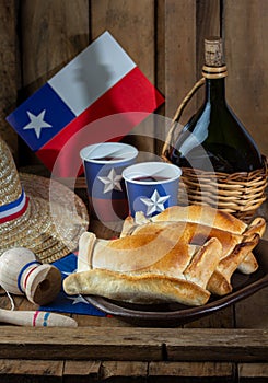 Chilean independence day concept. fiestas patrias. Tipical baked empanadas de pino, wine or chicha, hat and play emboque. Dish and photo